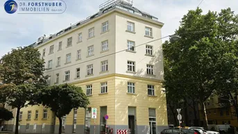 Mehrstöckiges Wohngebäude mit klassischer Fassade und vielen Fenstern in städtischer Umgebung.
