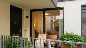 Gemütliche Terrasse im Erdgeschoss mit Sitzgelegenheiten und Pflanzenkübeln, umzäunt für Privatsphäre.