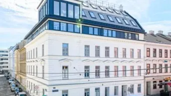 Modernisiertes Mehrfamilienhaus mit neuem Dachausbau und klassischer Fassade an einer Stadtstraße.
