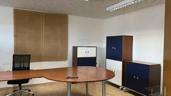 Geräumiges Büro mit Holzschreibtisch, Bürostuhl und blauen sowie weißen Schränken, ideal für produktives Arbeiten.