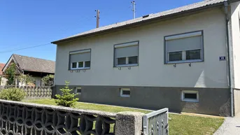 Seitenansicht eines Einfamilienhauses mit Fenstern, Rollläden und einem kleinen Vorgarten.