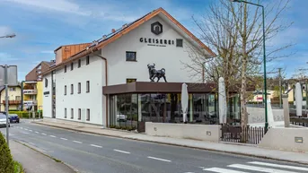 Modernes Gebäude mit markanter Architektur, großen Fenstern und einem Stier-Logo auf dem Dach.