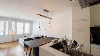 Moderne offene Wohnküche mit Essbereich, Holzboden und großen Fenstern.