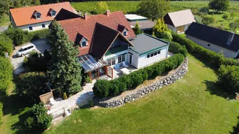 Vogelperspektive des Hauses mit rotem Ziegeldach, umgeben von grünen Weinbergen und Bäumen.