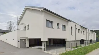 Moderne Reihenhäuser mit weißer Fassade und überdachtem Parkplatzbereich im Vordergrund.