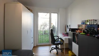 Helles Zimmer mit Schreibtisch, Schrank und Zugang zu einem französischen Balkon.