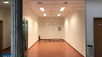 Leerer Geschäftsraum mit großer Glasfassade und braunem Bodenbelag, bereit zur individuellen Gestaltung.