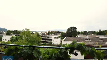 Balkon mit üppigem Grün und weitem Blick auf die Stadt, den See und die umliegende Landschaft.