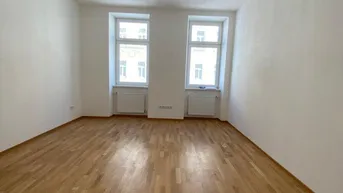 Heller, leerer Raum mit Parkettboden und zwei Fenstern, bereit zur individuellen Gestaltung.