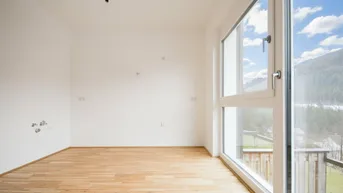 Geräumiges, helles Zimmer mit Holzboden und Zugang zu einem Balkon mit Bergblick.