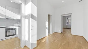 Offener Wohnbereich mit hellem Parkettboden und Blick auf eine moderne Küche.