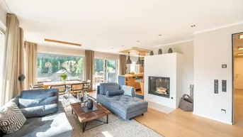 Helles, offenes Wohn-Esszimmer mit Kamin, bequemen Sofas und Zugang zur Terrasse.