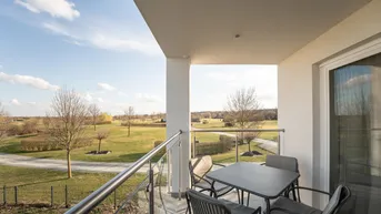 Moderner Balkon mit bequemen Sitzgelegenheiten und weitem Blick über grüne Felder und Bäume.