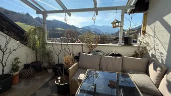 Überdachte Terrasse mit gemütlicher Sitzecke und herrlichem Bergblick unter einem Glasdach.