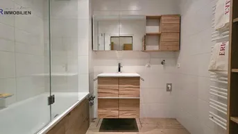 Modernes Badezimmer mit Badewanne, Duschwand, Holzwaschtisch und beheiztem Handtuchhalter.