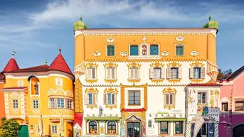 Farbenfrohe Fassade eines historischen Gebäudes mit kunstvollen Verzierungen und kleinen Balkonen.