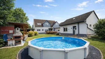 Großer Gartenbereich mit Aufstellpool, Grillplatz und Blick auf das Wohnhaus unter blauem Himmel.
