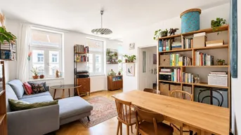 Helles Wohn- und Esszimmer mit Fischgrätparkett, gemütlichem Sofa und großem Esstisch.