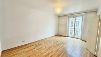 Helles Zimmer mit Holzboden, weißen Wänden und Zugang zu einem französischen Balkon.