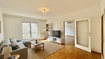 Helles Wohnzimmer mit Parkettboden, gemütlichem Sofa und Zugang zu einem Balkon.