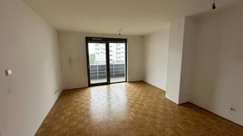 Helles Zimmer mit Parkettboden und Zugang zu einem Balkon, ideal als Wohn- oder Schlafzimmer.