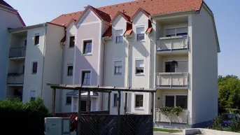 Mehrstöckiges Wohngebäude mit hellen Fassaden, roten Ziegeldächern und mehreren Balkonen.