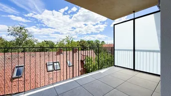 Geräumiger Balkon mit Fliesenboden und weitem Blick über die Dächer und Bäume.