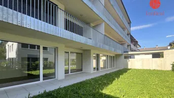 Moderne Wohnanlage mit Balkonen und Grünfläche im Erdgeschoss.