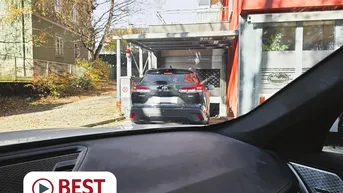 Einfahrt zu einer überdachten Parkmöglichkeit mit einem Fahrzeug im Vordergrund.