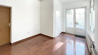 Heller Büroraum mit glänzendem Fliesenboden, weißen Wänden und doppelten Glastüren zum Außenbereich.