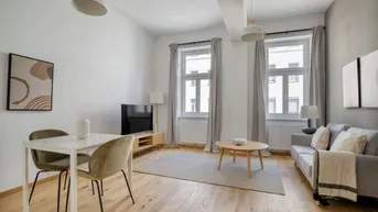 Helles Wohn- und Esszimmer mit Parkettboden, modernen Möbeln und zwei großen Fenstern.