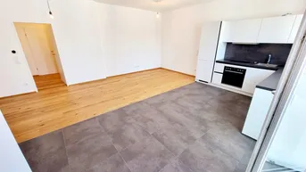 Heller Wohn-Essbereich mit moderner Einbauküche, Parkettboden und Fliesenbereich.