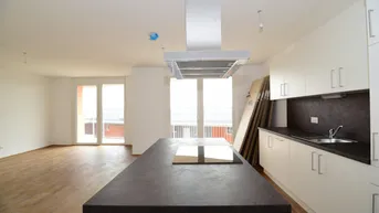 Moderne Einbauküche mit Kochinsel und Holzboden in einem hellen, offenen Wohnbereich.