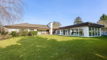 Weitläufiger Garten mit gepflegtem Rasen und moderner Glaserweiterung des Hauses.