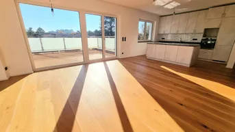 Heller, offener Wohn- und Essbereich mit Holzboden und Zugang zu einer großen Terrasse.