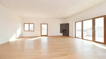 Heller, leerer Wohnraum mit Holzboden, integriertem Kamin und großen Fenstern mit Terrassenzugang.