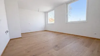 Helles, leeres Zimmer mit Holzboden und großen Fenstern, bereit zur individuellen Gestaltung.