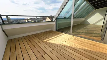 Sonnige Dachterrasse mit Holzboden und Blick über die Stadt, ideal zum Entspannen.