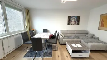 Geräumiger Wohn-Essbereich mit hellem Parkettboden und großem Fenster.