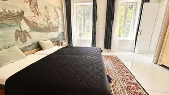 Geräumiges Schlafzimmer mit großem Wandteppich, zwei Einzelbetten und Blick ins Grüne.
