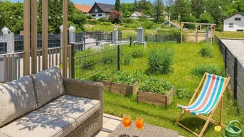 Gemütliche Terrasse mit Lounge-Möbeln, Pergola und Blick auf den Garten mit Hochbeeten.