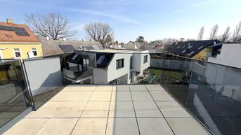 Geräumige Dachterrasse mit Fliesenboden und Glasgeländer, bietet einen weiten Blick über die Umgebung.