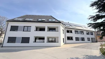 Neubau-Wohngebäude mit moderner Architektur, mehreren Balkonen und Photovoltaikanlage auf dem Dach.