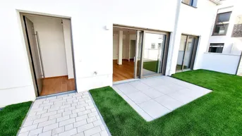 Blick auf die gepflasterte Terrasse und den kleinen Gartenbereich eines modernen Reihenhauses.