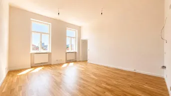 Helles, leeres Zimmer mit Parkettboden und zwei großen Fenstern, die viel Tageslicht hereinlassen.