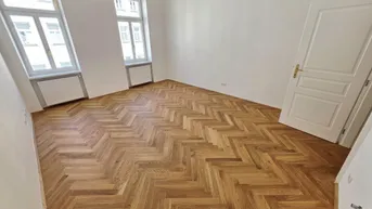 Helles Zimmer mit Fischgrätparkett und zwei Fenstern, ideal als Wohn- oder Schlafzimmer nutzbar.