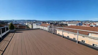 Große Dachterrasse mit Holzdielenboden und weitem Blick über die Stadt.