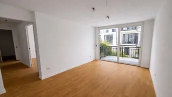 Helles, unmöbliertes Wohnzimmer mit Holzboden und großem Fenster zum Balkon.