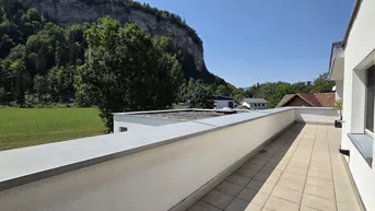 Weitläufiger Blick von der Terrasse auf grüne Felder und eine beeindruckende Felswand.