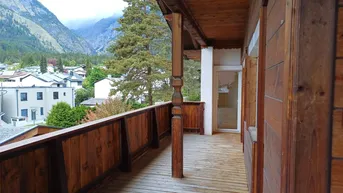 Geräumiger Holz-Balkon mit traditionellem Geländer und beeindruckendem Bergblick.